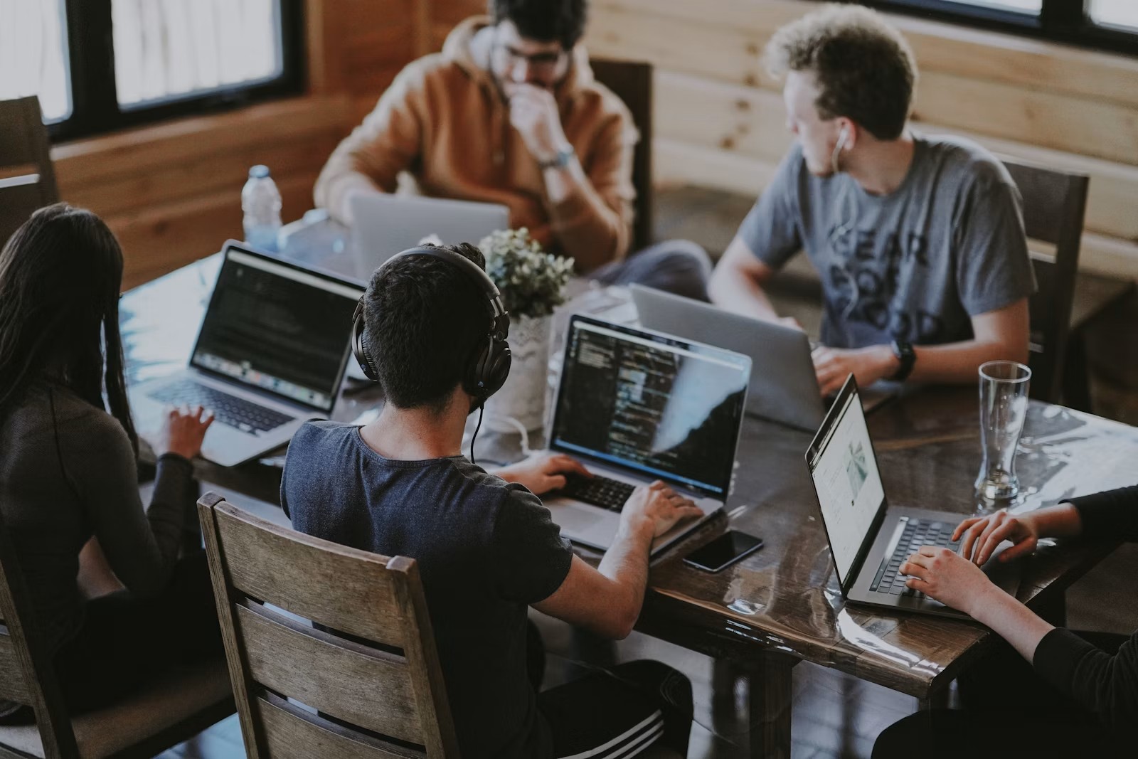 Plusieurs personnes autours d'un bureau avec des ordinateurs portables