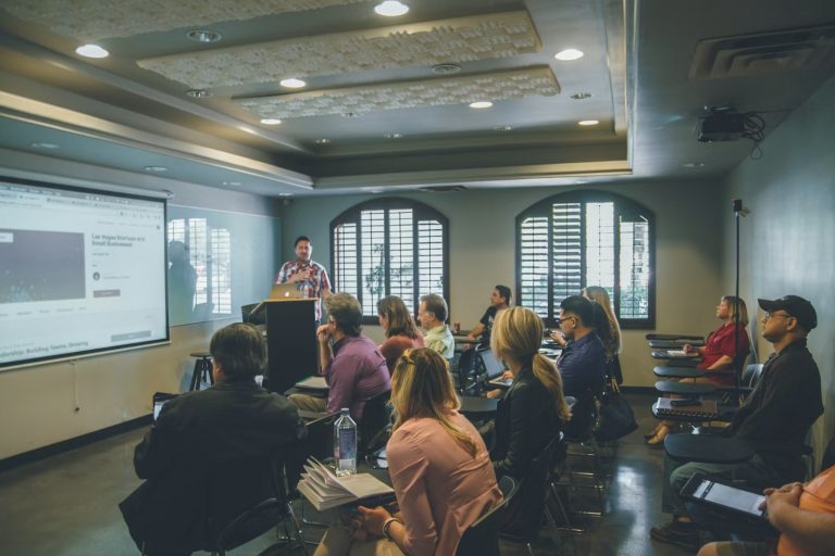 Une salle de formation avec un tableau numérique, un intervenant et des apprenants